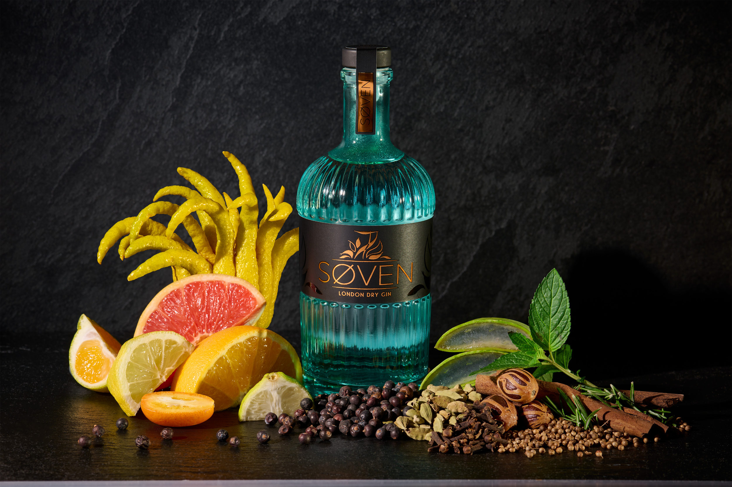 SØVEN GIN Flasche mit Zitrusfrüchten und Botanicals